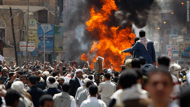 Protesters gather around a burning vehicle belonging to government supporters during a protest in Sanaa on Tuesday.