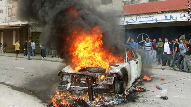 Lebanese men gather around a burning police car during a protest in the southern port city of Tyre on Thursday.