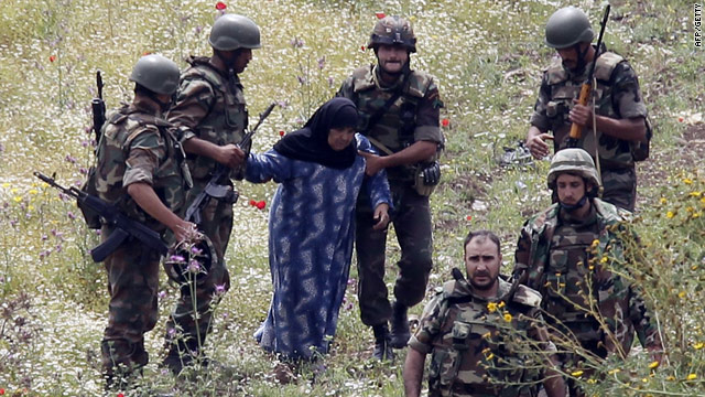 Syrian soldiers prepare to hand over an elderly Syrian woman who was caught trying to cross the border into northern Lebanon.