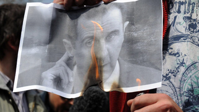 A Syrian opposition protester burns an image of President Bashar al-Assad.
