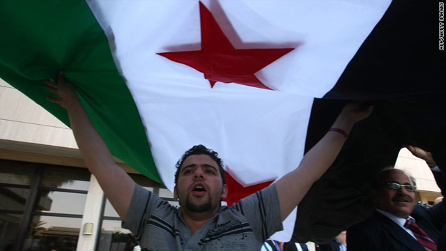 A member of Syrian opposition shouts slogans under a former Syrian flag to protest against President Bashar al-Assad.