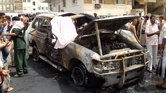 Yemenis look at a destroyed vehicle following a car bomb that killed a British man in Aden, Yemen, on July 20.