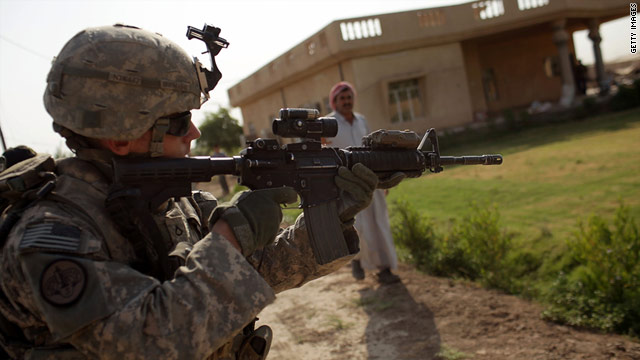 A U.S. soldier takes aim at a charging dog while on a patrol this month in Iskandariya, Iraq.