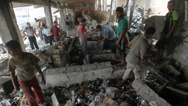 Iraqis walk through a decimated liquor store after a car bombing (Photo courtesy of CNN).
