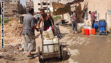 سوريون يملأون حاويات مياه في منطقة تسيطر عليها المعارضة بمخيم اليرموك على المشارف الجنوبية لدمشق