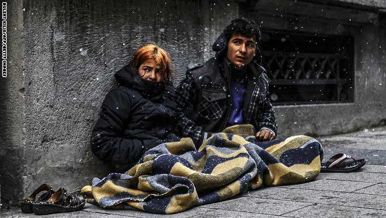 لاجئون سوريون يجلسون على الرصيف تحت الثلوج في اسطنبول
