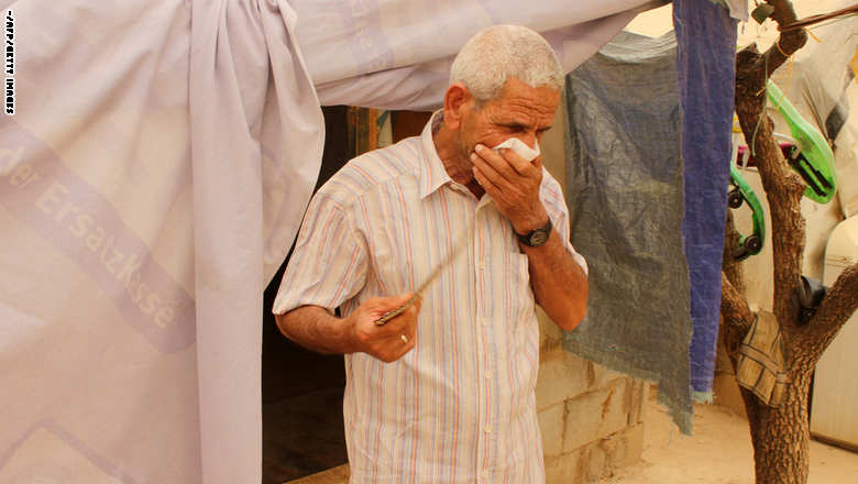 لاجئ سوري يغطي وجهه ليحمي نفسه من الغبار أثناء عاصفة رملية في مخيم للاجئين بالقرب من تعلبايا