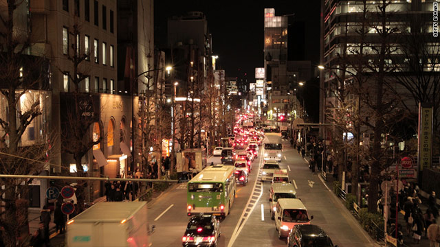 Pedestrians and cars make their way in Tokyo after train services are suspended following the earthquake.