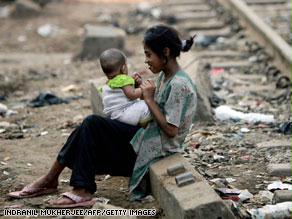 فتاة هندية تداعب طفلها قرب خط للقطارات