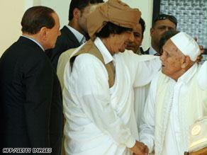 القذافي يسلم على محمد بن عمر المختار ومعهما رئيس الوزراء الإيطالي