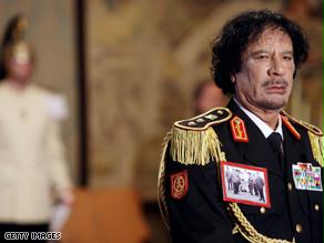 القذافي ببدلته العسكرية وصورة عمر المختار على صدره
