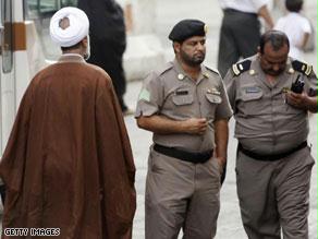 حاج شيعي يمشي قرب اثنين من رجال الشرطة السعوديين