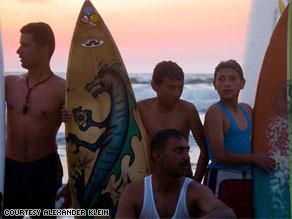 مجموعة من الشباب يقفون إلى جانب ألواحهم على شاطئ البحر