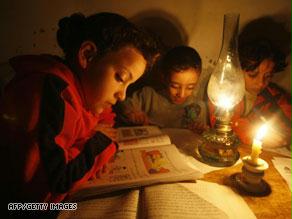 أطفال يدرسون على ضوء الشموع والقناديل بغزة