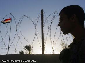 جندي إسرائيلي يراقب موقعاً للشرطة المصرية على الجانب الآخر من الحدود