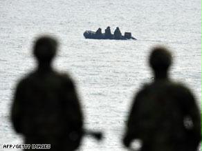 عناصر من قوات البحرية الكورية الجنوبية تراقب قاربا كوريا شماليا