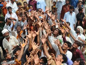 باكستانيون يمدون أيديهم لتلقي مساعدات غذائية