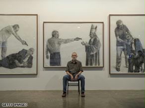 جيل فينسنتي يجلس أمام ثلاثة من لوحاته
