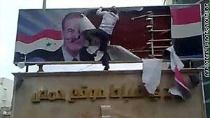 محتج يمزق صورة للأسد ووالده في حمص