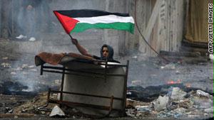 فلسطيني يرفع العلم خلال مواجهات مع القوات الإسرائيلية في الضفة الغربية