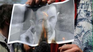 أحد المتظاهرين يشعل النار بصورة الرئيس السوري بشار الأسد