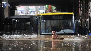 رجل صيني يشق طريقه وسط مياه الفيضانات التي غمرت حافلات بأكملها